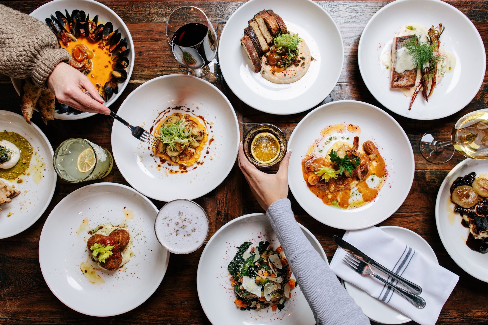 A bird's-eye view showcases a bountiful spread of delicious dishes and beverages on a rustic wooden table, ideal for food blogs, restaurant promotions, or lifestyle content